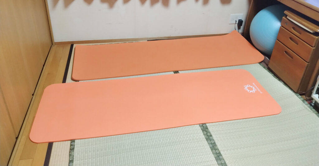 畳の上に並べたオレンジ色のヨガマット2枚と奥のバランスボール