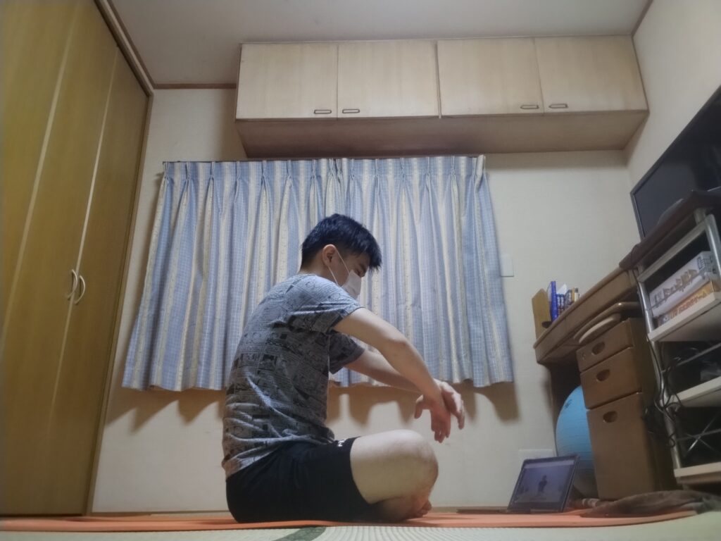 安楽座（Sukhasana）で背中を丸めて腕を前に伸ばすストレッチポーズ