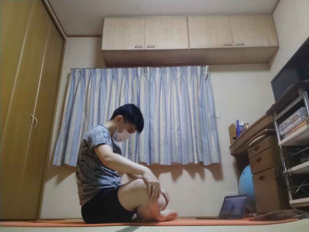 安楽座（Sukhasana）で背中を丸めて両手を膝に置くストレッチポーズ