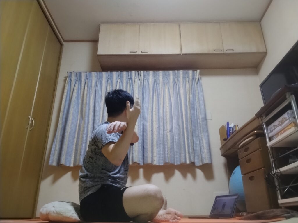 安楽座（Sukhasana）で腕を横に広げて上体をひねるツイストポーズ