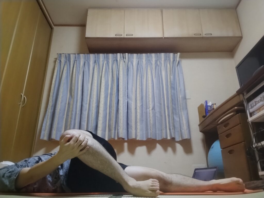 仰向けに寝て左を見て安楽座をとるリラックスポーズ