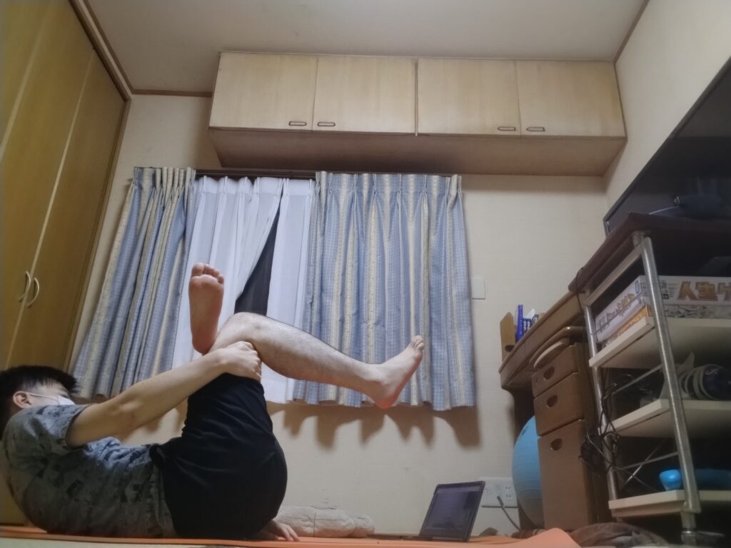 SOELUオンラインヨガでフィギュア4ポーズを取りながら、体幹を使って上半身を起こしている男性。