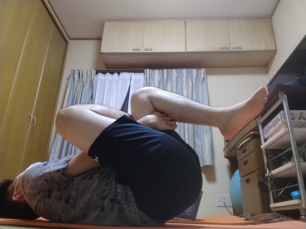 SOELUのオンラインヨガで仰向けのフィギュア4ポーズを行う男性。股関節やお尻まわりをゆるめている様子。