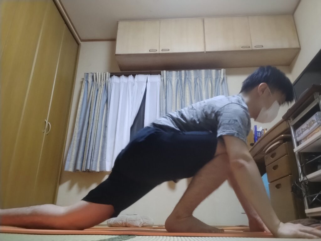 右脚を前に出し、左脚を後ろに伸ばしたローランジの姿勢で股関節をストレッチしている男性。