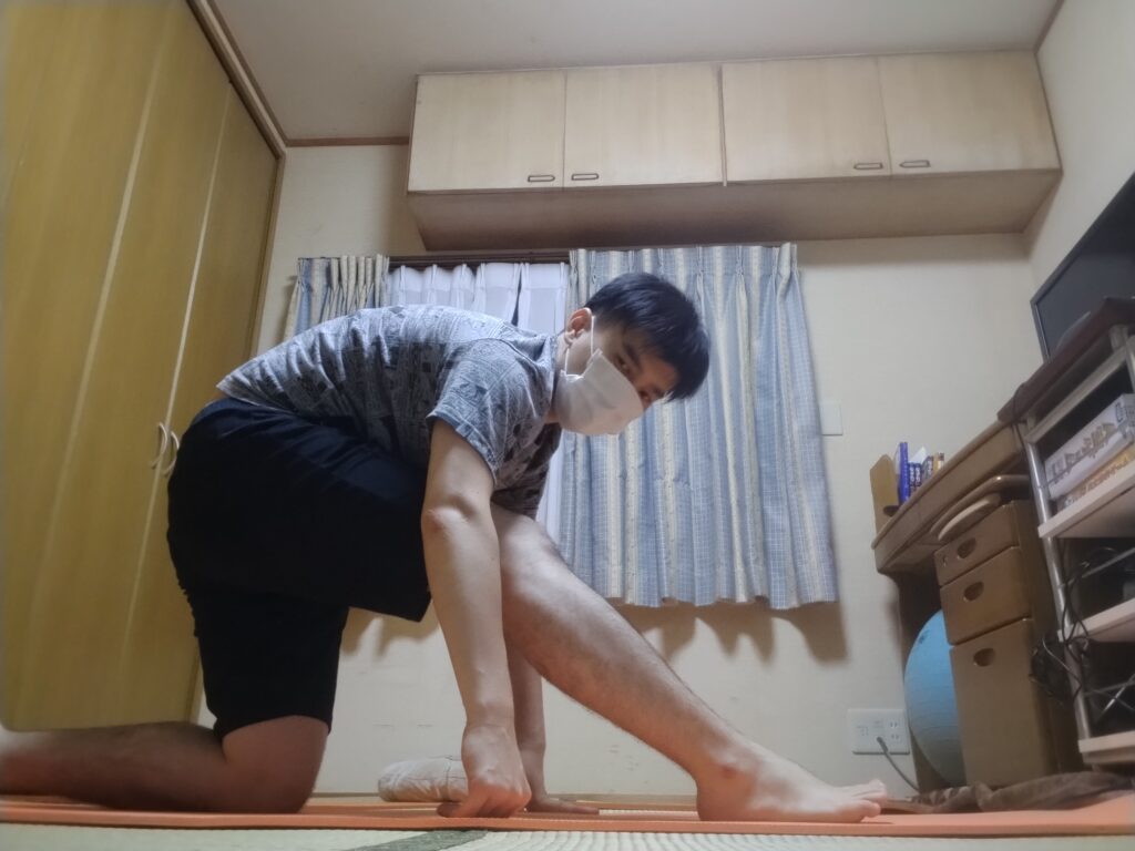左脚を前に出し、右膝をついた状態で前屈しながらハムストリングをストレッチしている男性。