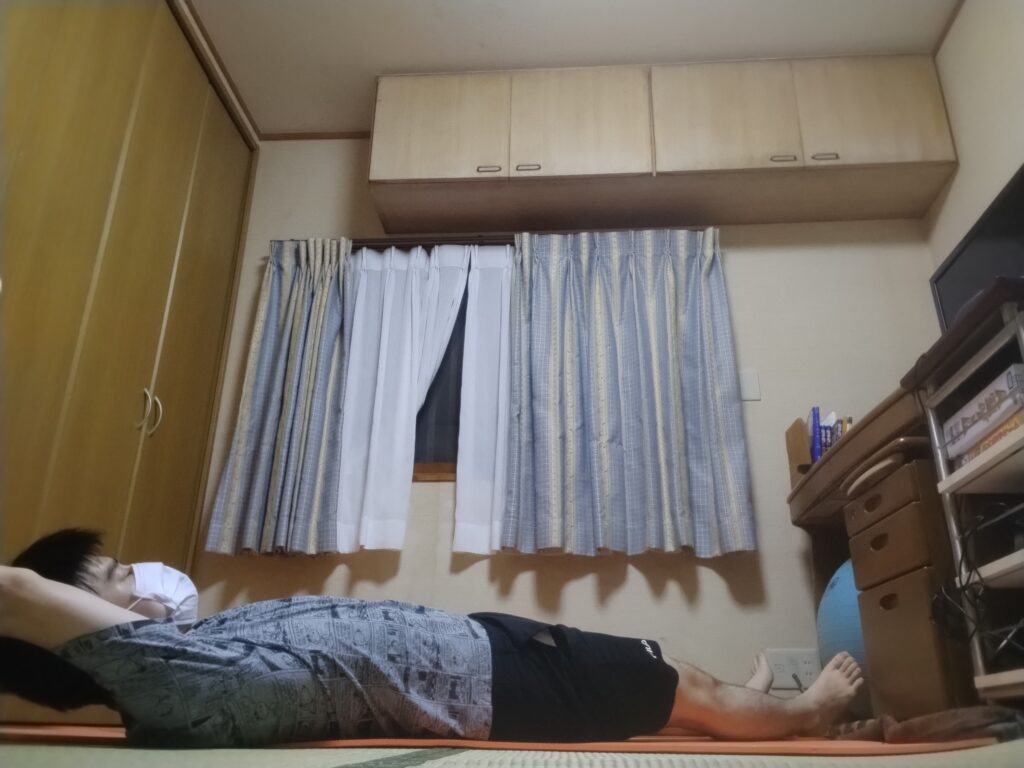 ヨガレッスンの最後に、仰向けでリラックスしているシャヴァーサナのポーズを行っている男性。