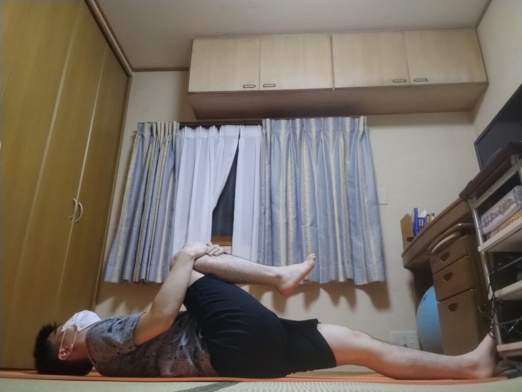 SOELUのストレッチレッスンで片足の膝を胸に引き寄せているポーズを行っている様子。