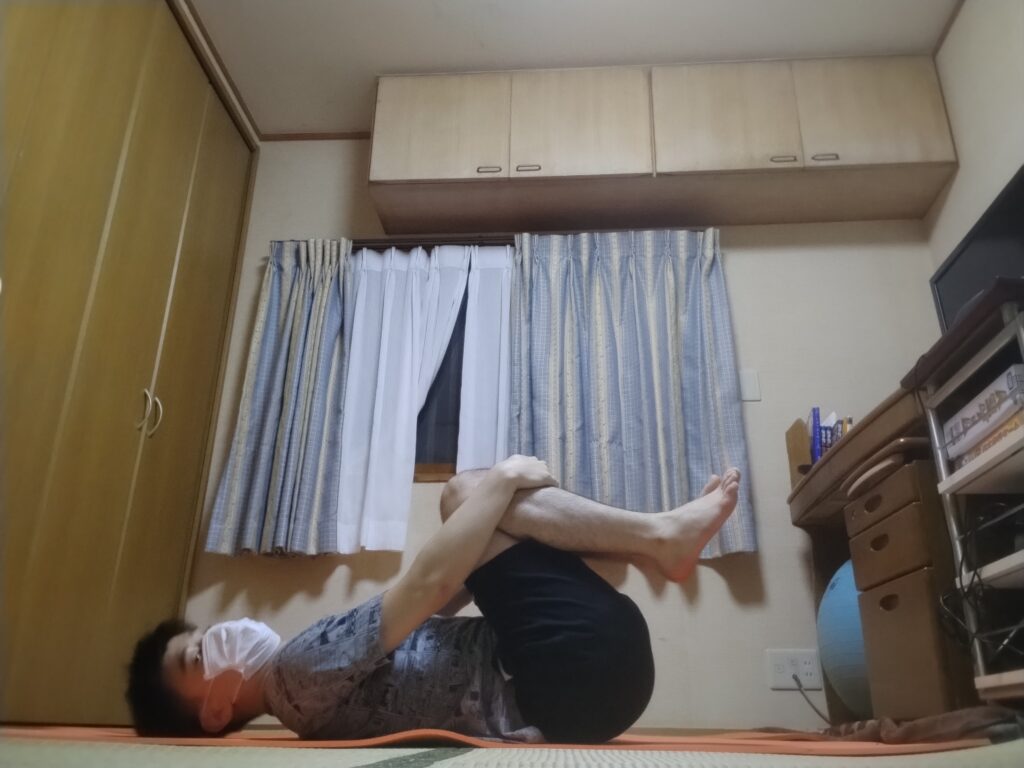 SOELUのレッスンで「ガス抜きのポーズ」をとっている様子。仰向けで両膝を胸に引き寄せている。