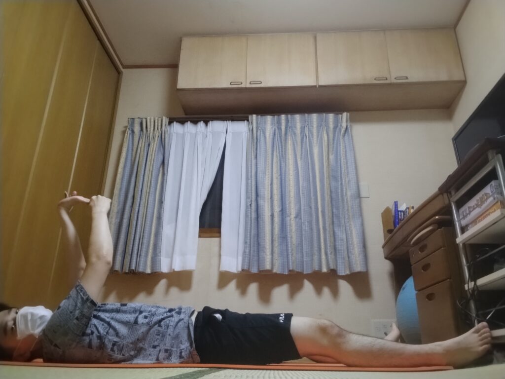 仰向けで手首をストレッチしている男性
