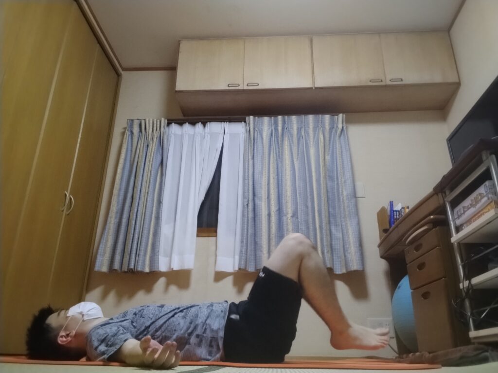 仰向けで両膝を立ててリラックスしている男性。