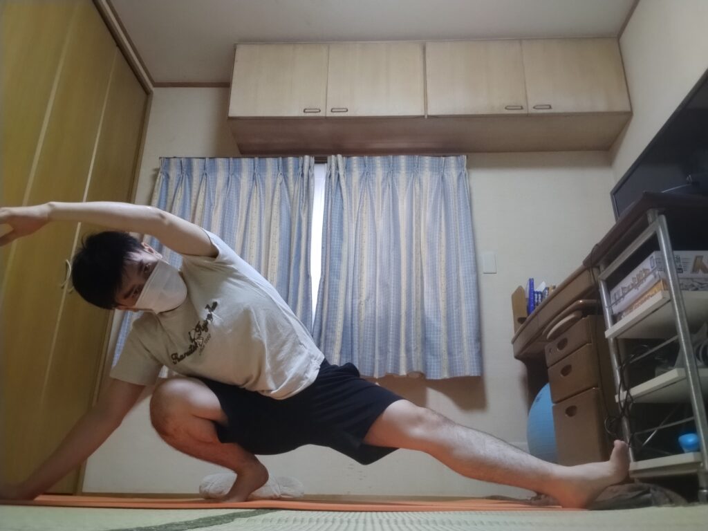 サイドランジ姿勢で腕を伸ばし体側をストレッチしている男性