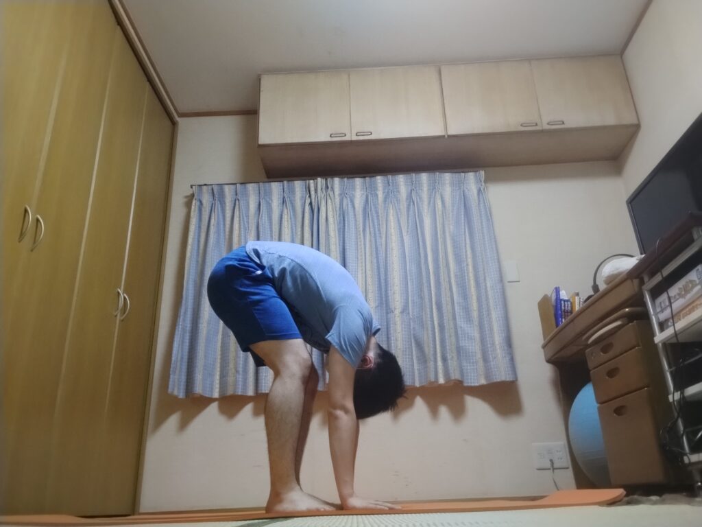 前屈のポーズ（ウッターナーサナ）を行う男性