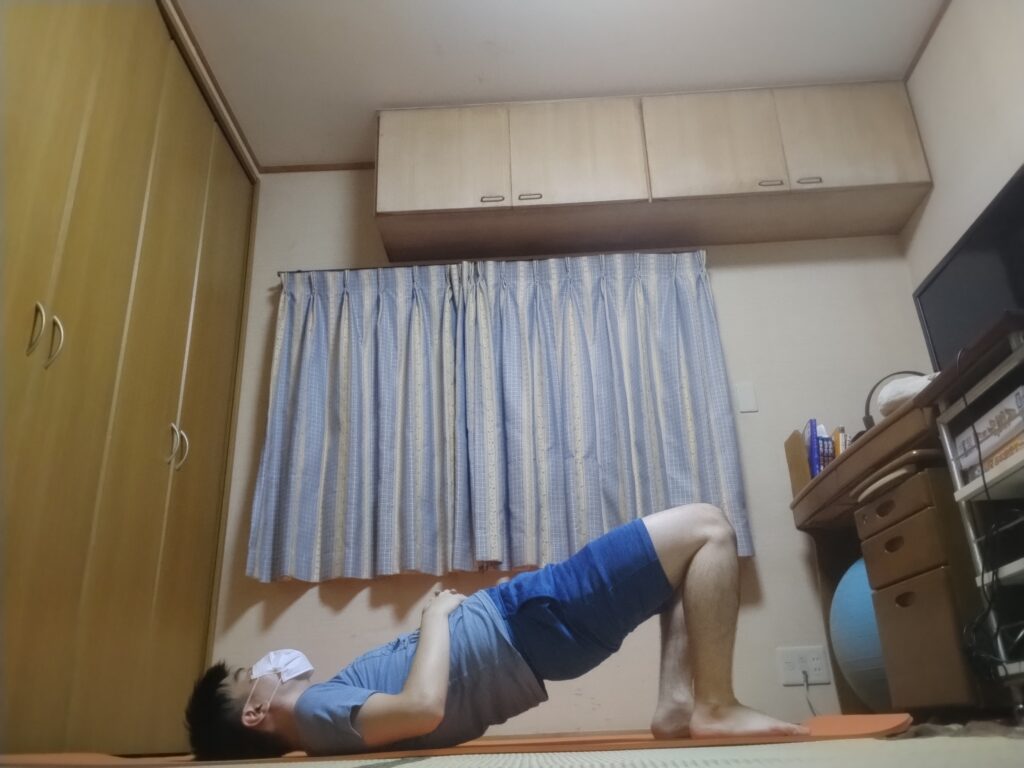 ブリッジのポーズで腰を持ち上げて胸を開く男性のヨガポーズ