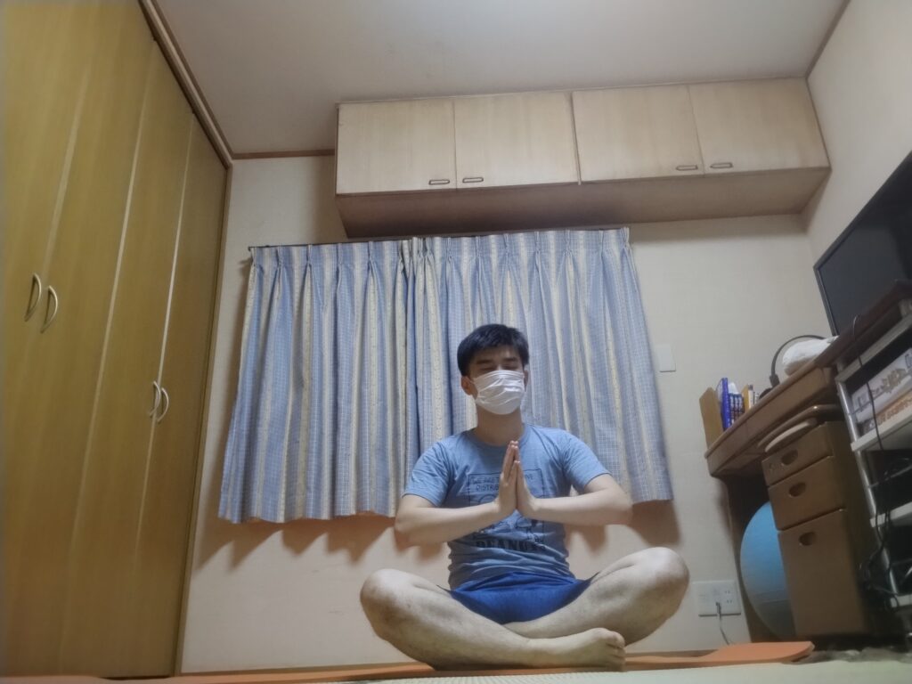 安楽座で合掌しながら目を閉じる男性