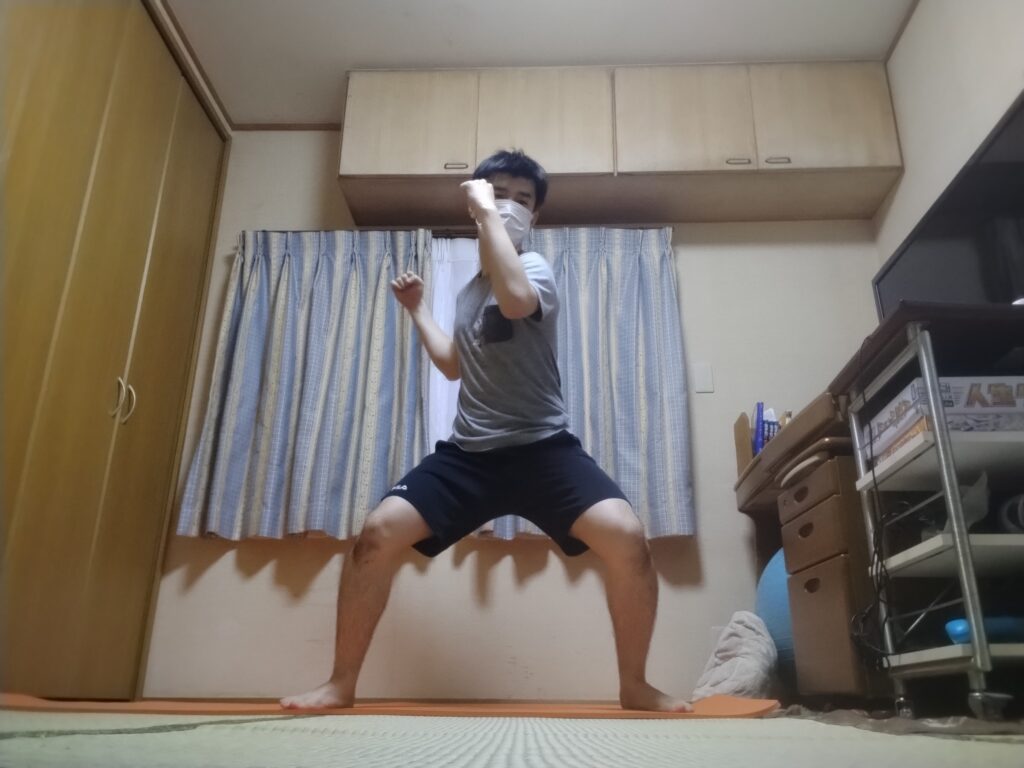 SOELUフィットネスレッスンで足を広げて腰を落とし、両腕を構えたファイティングスタンス