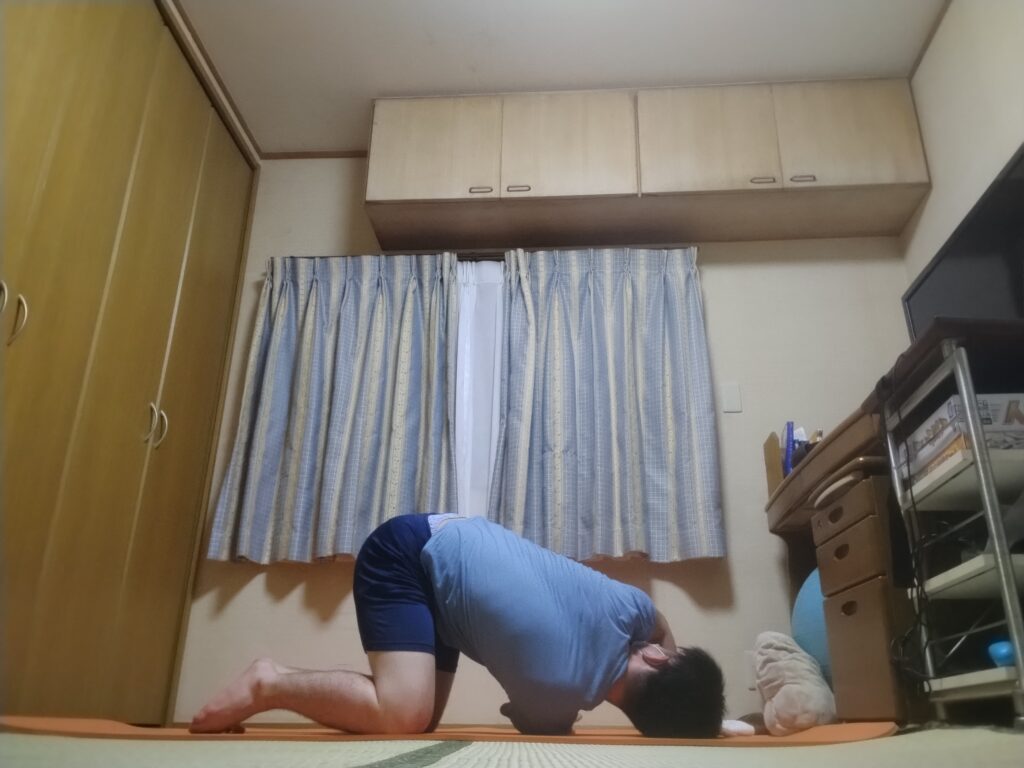 SOELUのオンラインヨガで四つん這いから腕を通すスレッド・ザ・ニードルのポーズを行い、肩と背中をストレッチしている様子